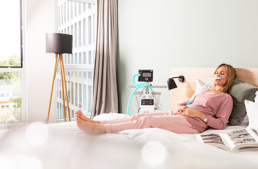 Woman resting comfortably in bed wearing a CPAP mask connected to a CPAP machine