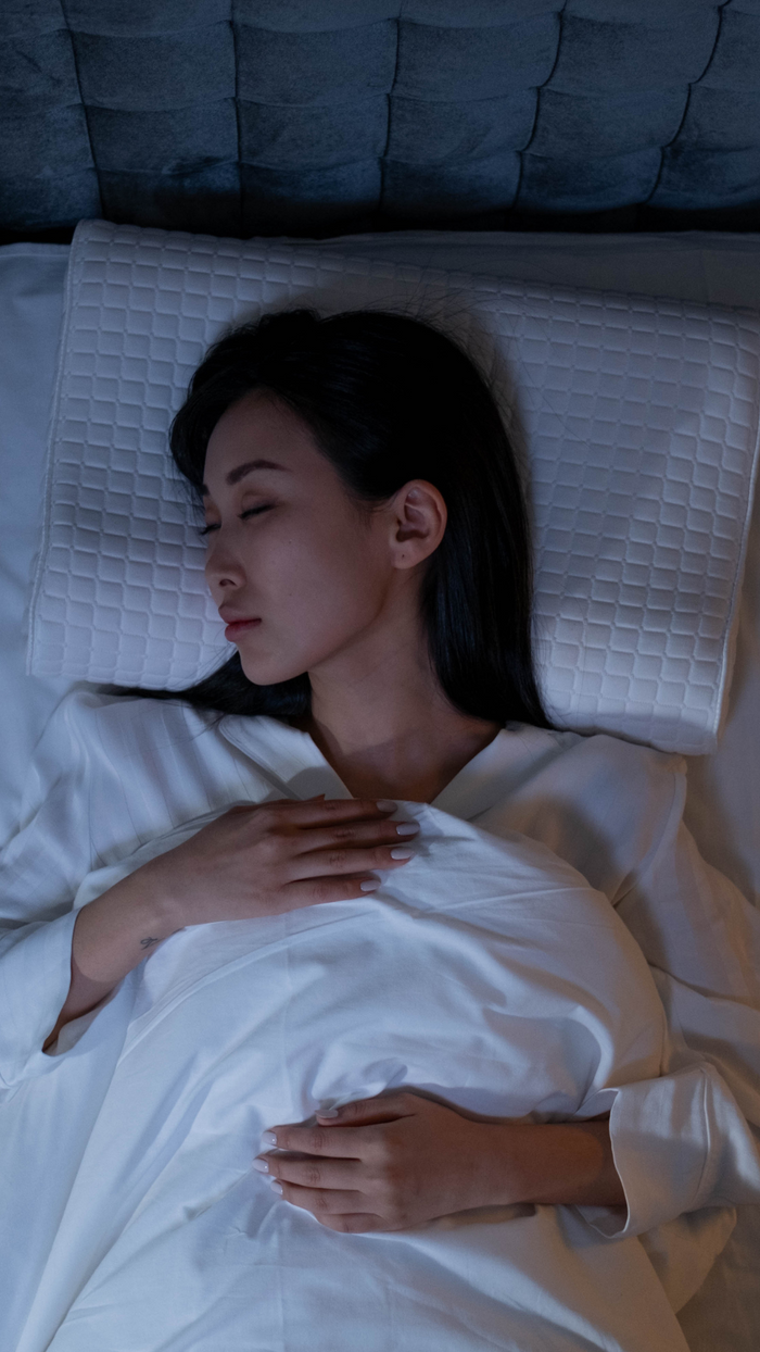 Woman sleeping peacefully on a bed with white bedding